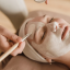 Alt Text: Εφαρμογή μάσκας ομορφιάς στο πρόσωπο γυναίκας Applying beauty mask on woman's face